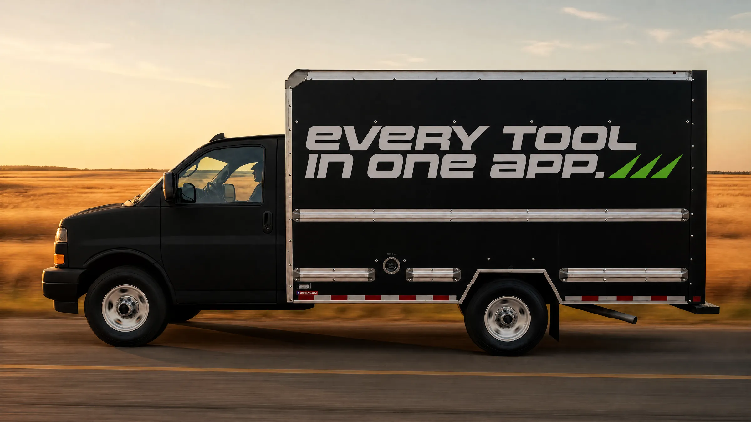 A matte black box truck reading EVERY TOOL IN ONE APP driving through open country